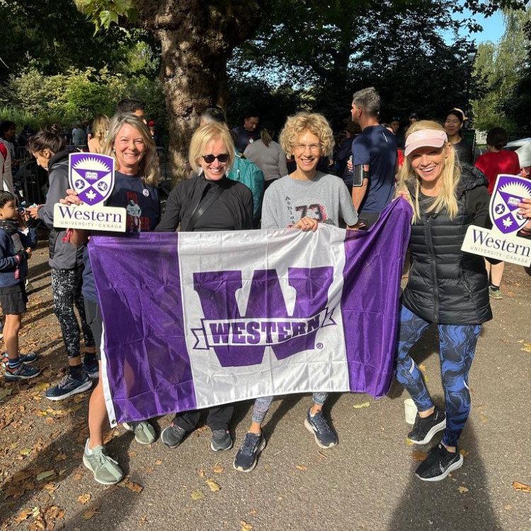4 proud alumni holding a Western flag